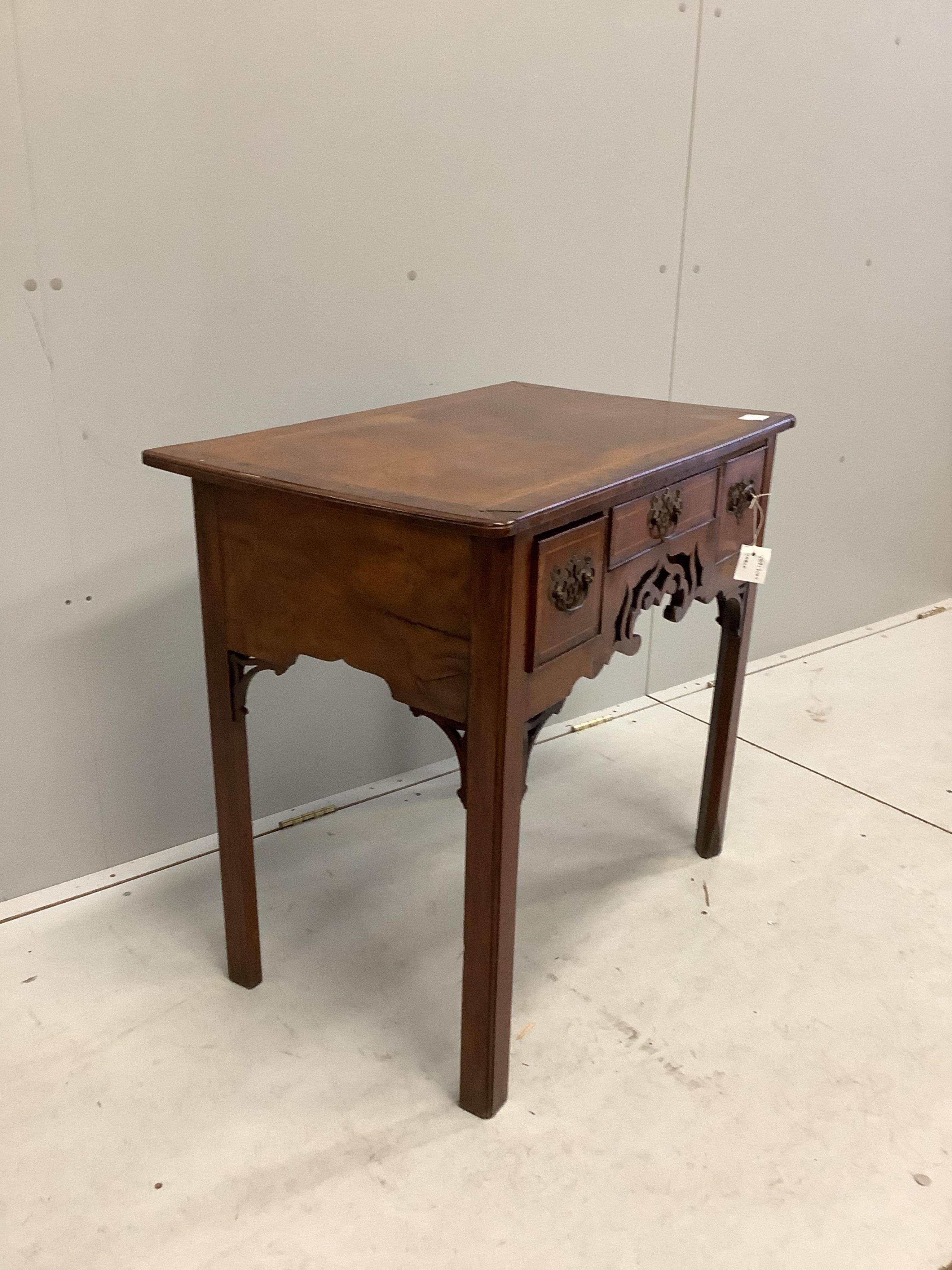 A mid 18th century walnut lowboy quarter veneered with a rectangular top above three drawers and a pierced apron on chamfered legs, width 80cm, depth 49cm, height 73cm. Condition - poor to fair